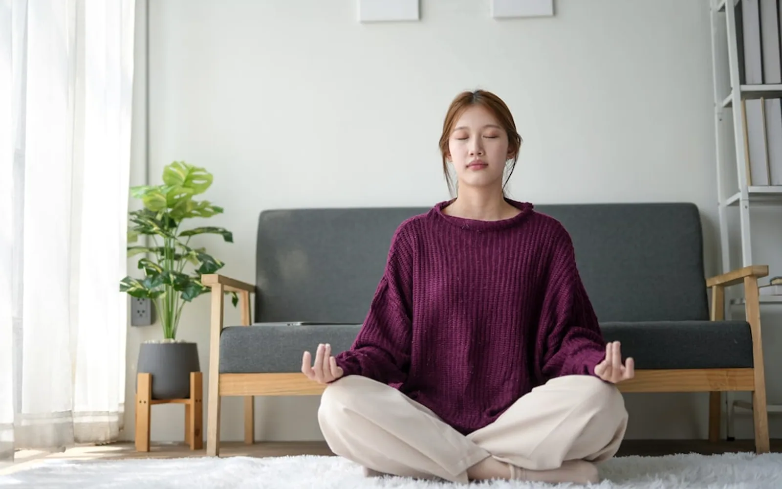 Frau im Schneidersitz mit geschlossenen Augen, ruhige Pranayama-Praxis im Tageslicht
