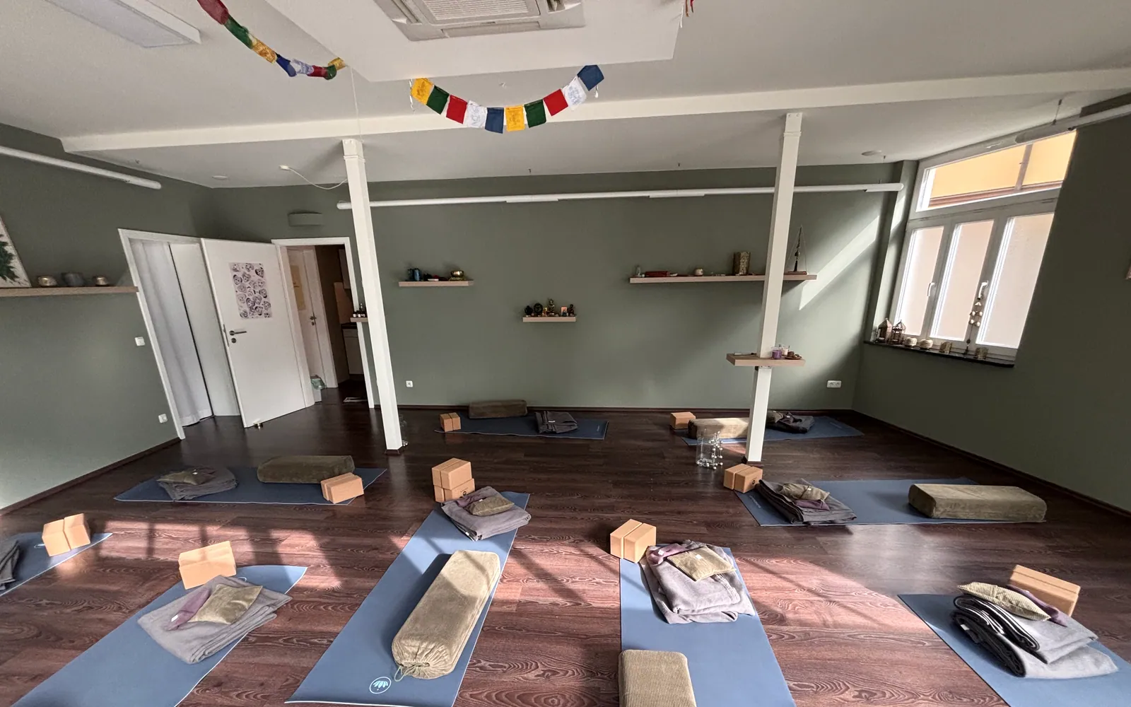 Vorbereiteter Yoga-Studio-Raum in Arnstadt mit Matten, Yoga-Blöcken und Bolster im Morgenlicht